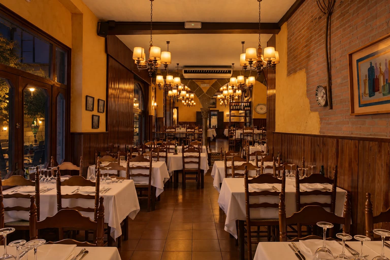 Dining room of La Font de Prades restaurant inside Poble Espanyol, Barcelona, lamps lit and tables set for a corporate dinner