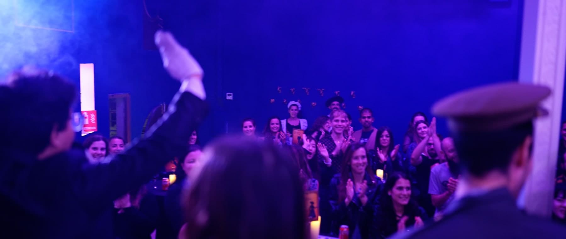 Large corporate audience applauding at the end of a live murder mystery show in Barcelona
