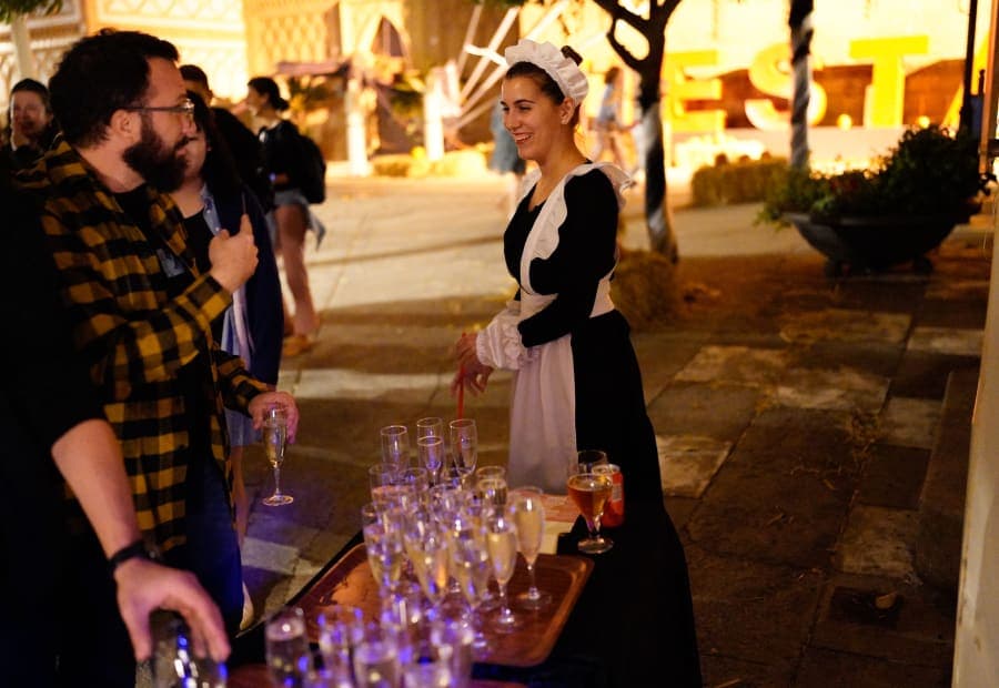 Actress in maid costume serving cava at a corporate after-work murder mystery at Poble Espanyol